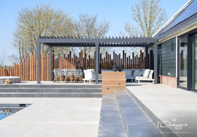 Lamellen overkapping grijs in moderne achtertuin met maatwerk houten achterwand